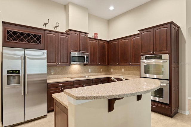 3320 Majestic View Dr, Lutz, FL 33558 - kitchen featuring stainless steel appliances, dark brown cabinetry, tasteful backsplash, a kitchen island with sink, and a breakfast bar