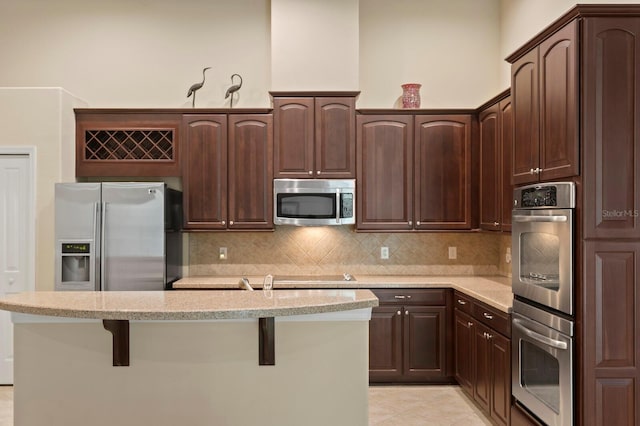 3320 Majestic View Dr, Lutz, FL 33558 - kitchen featuring stainless steel appliances, dark brown cabinetry, tasteful backsplash, and a kitchen island with sink