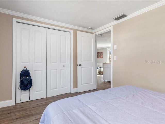 bedroom featuring dark wood-type flooring, crown molding, and a closet