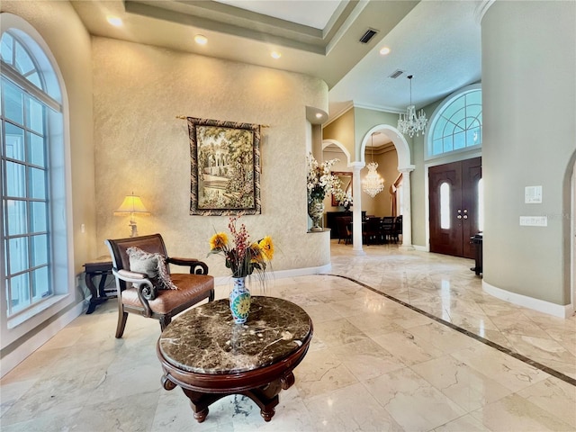 foyer entrance featuring crown molding, a towering ceiling, and a chandelier