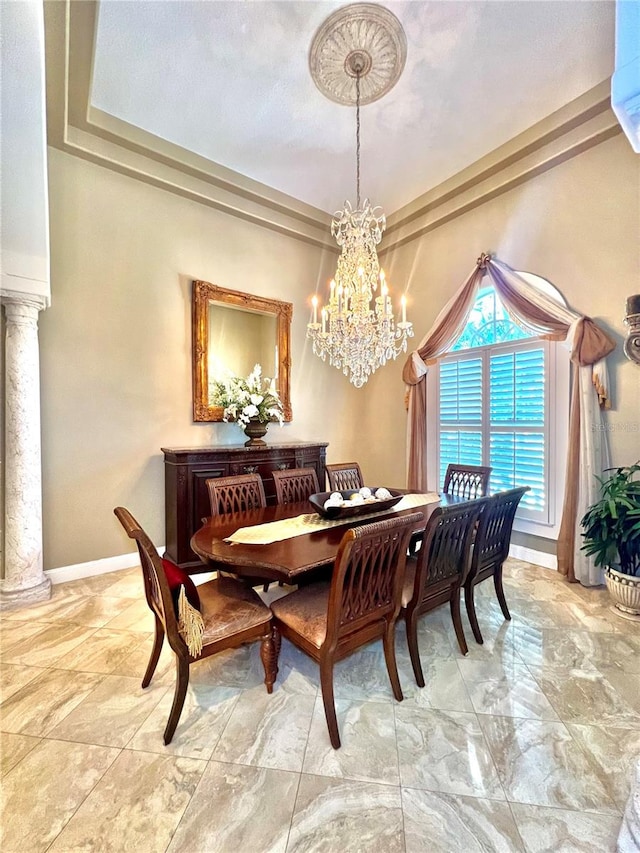 dining area with a tray ceiling, ornate columns, and an inviting chandelier