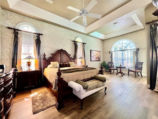 bedroom featuring ceiling fan, light hardwood / wood-style floors, and a raised ceiling