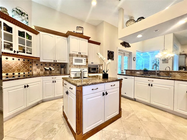 kitchen with white cabinetry, sink, an inviting chandelier, pendant lighting, and white appliances