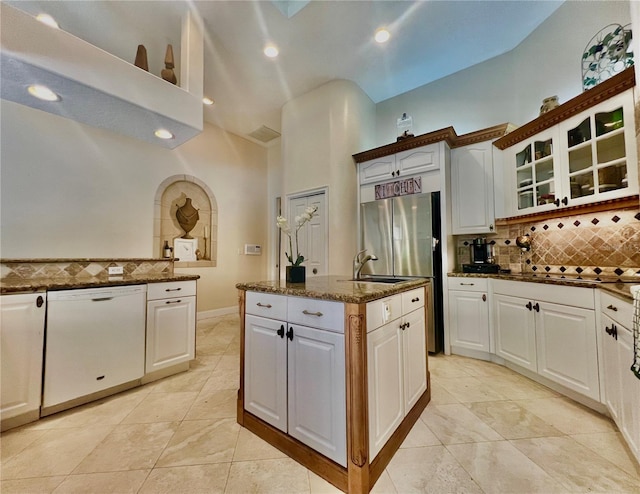 kitchen featuring white cabinets, dark stone counters, sink, dishwasher, and a high ceiling