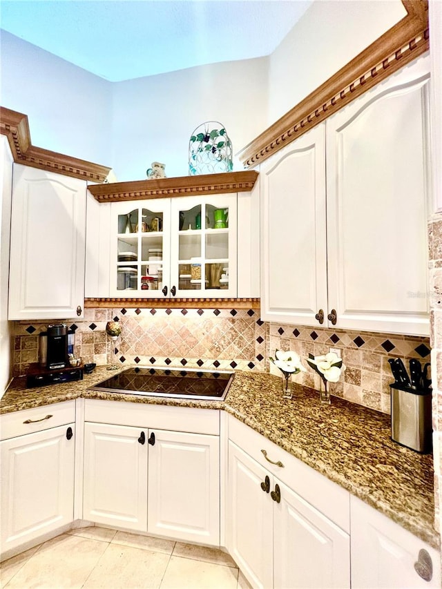 kitchen featuring cooktop, decorative backsplash, white cabinetry, and light tile patterned flooring