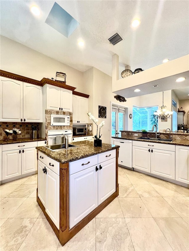 kitchen with white cabinets, white appliances, sink, and a skylight