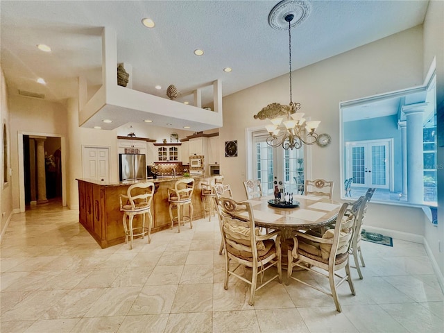 dining room featuring a chandelier, french doors, a towering ceiling, and a textured ceiling