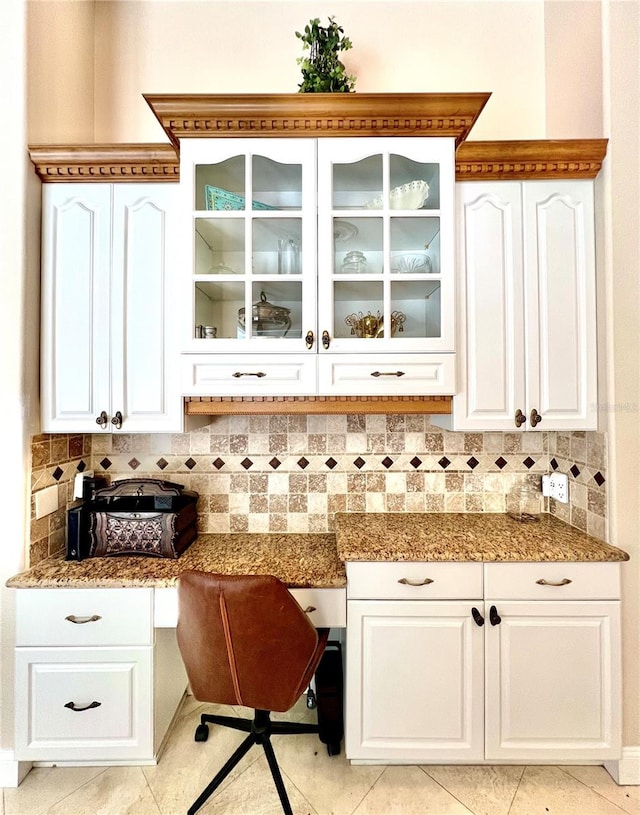 bar featuring built in desk, tasteful backsplash, white cabinetry, and light tile patterned flooring