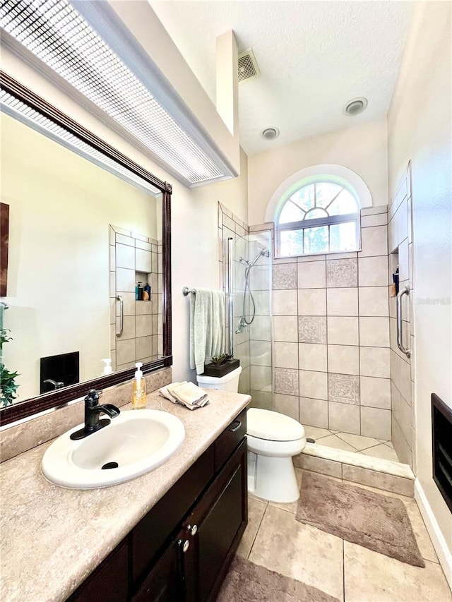 bathroom featuring tile patterned flooring, vanity, an enclosed shower, and toilet