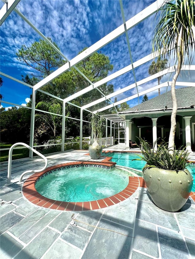 view of pool with a lanai, a patio, and an in ground hot tub