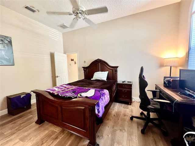 bedroom with ceiling fan, light hardwood / wood-style floors, and a textured ceiling