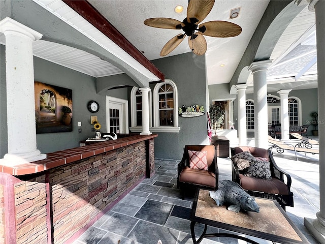 bar featuring a textured ceiling, decorative columns, and ceiling fan