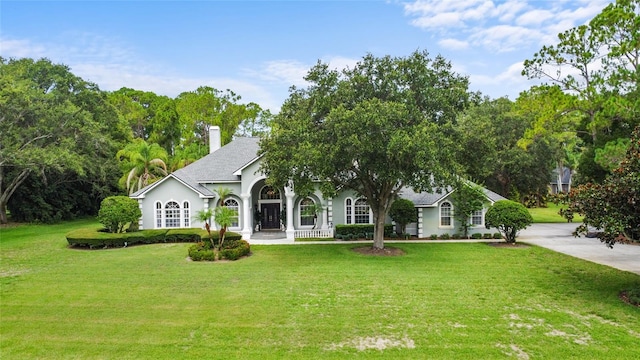 168 Rue Des Chateaux, Tarpon Springs, FL 34688 - single story home featuring a front lawn, a chimney, stucco siding, and roof with shingles