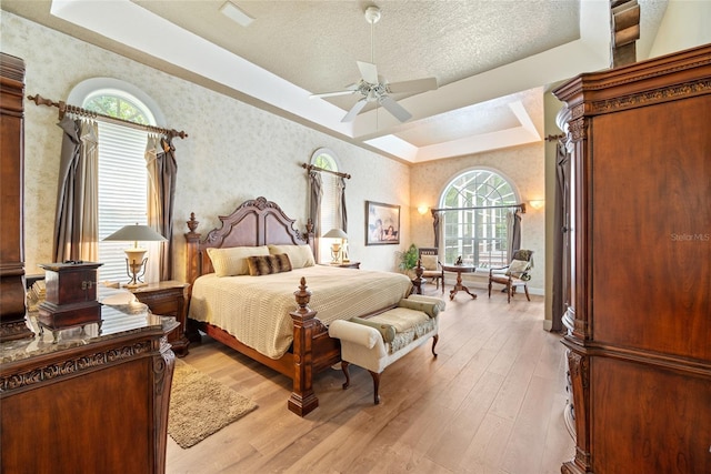 168 Rue Des Chateaux, Tarpon Springs, FL 34688 - bedroom featuring wallpapered walls, light wood finished floors, a raised ceiling, ceiling fan, and a textured ceiling