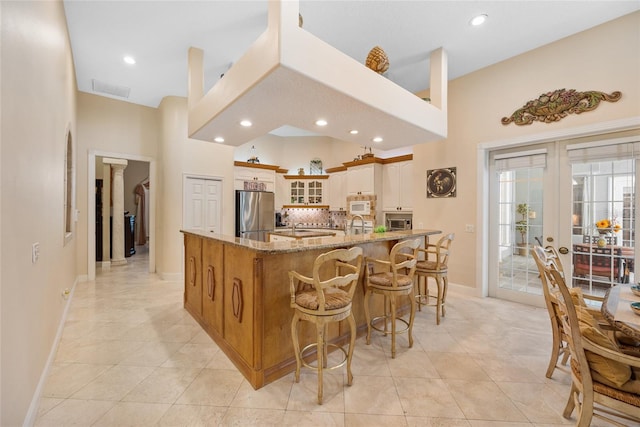168 Rue Des Chateaux, Tarpon Springs, FL 34688 - kitchen with appliances with stainless steel finishes, glass insert cabinets, light stone countertops, light tile patterned floors, and recessed lighting