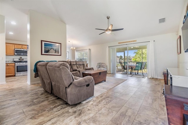 living room featuring lofted ceiling and ceiling fan with notable chandelier