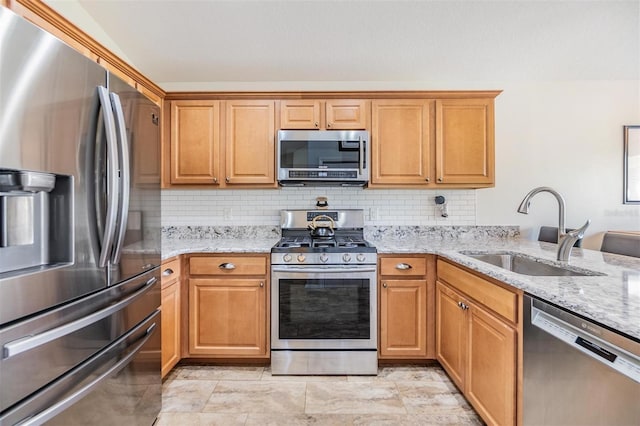 kitchen with stainless steel appliances, tasteful backsplash, light stone countertops, and sink