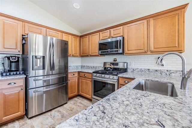 kitchen featuring sink, vaulted ceiling, appliances with stainless steel finishes, light stone countertops, and backsplash