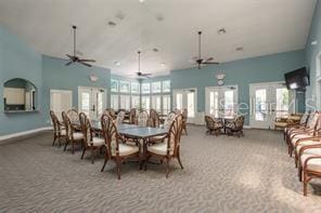 carpeted dining space with a towering ceiling, ceiling fan, and french doors