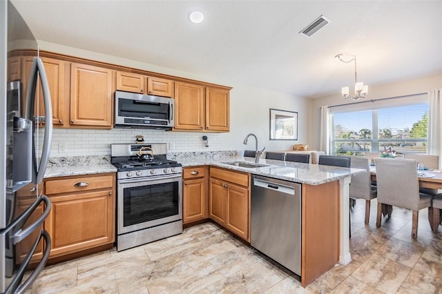 kitchen with appliances with stainless steel finishes, decorative light fixtures, sink, kitchen peninsula, and light stone countertops