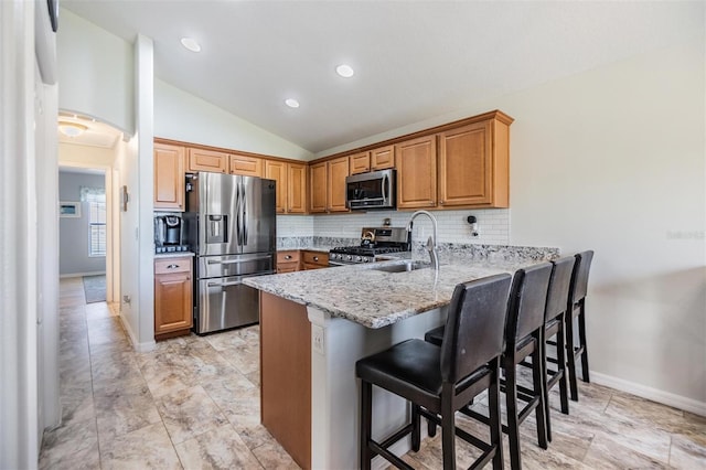 kitchen featuring appliances with stainless steel finishes, backsplash, light stone countertops, a kitchen bar, and kitchen peninsula