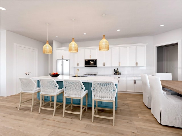 kitchen featuring a kitchen island with sink, white cabinets, decorative light fixtures, and stainless steel appliances