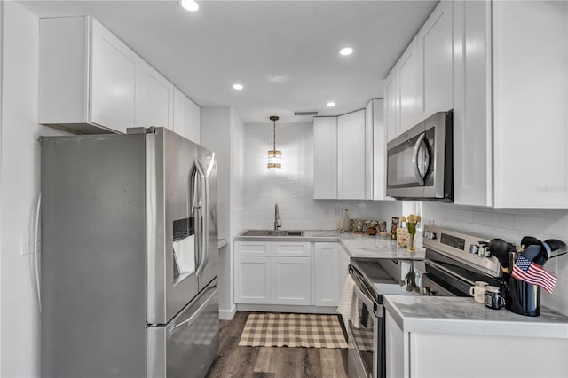 kitchen featuring pendant lighting, sink, dark wood-type flooring, white cabinetry, and stainless steel appliances