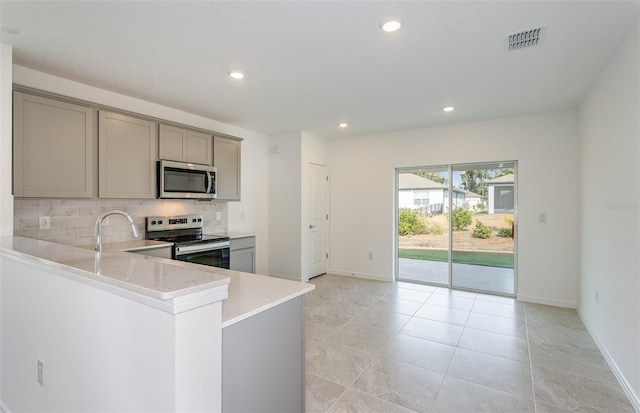 kitchen featuring kitchen peninsula, appliances with stainless steel finishes, backsplash, sink, and gray cabinets