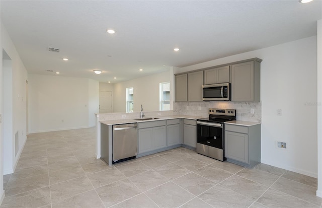 kitchen with gray cabinetry, sink, stainless steel appliances, tasteful backsplash, and light tile patterned floors