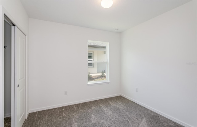 unfurnished bedroom featuring dark carpet and a closet