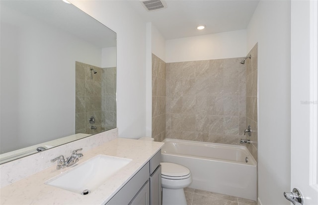 full bathroom with tile patterned flooring, vanity, tiled shower / bath combo, and toilet