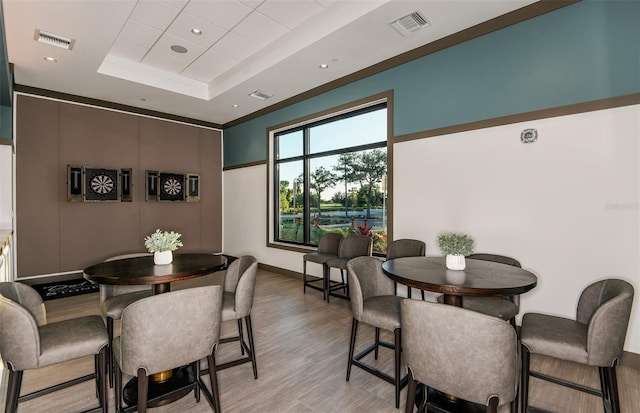 dining area with light hardwood / wood-style flooring and a raised ceiling