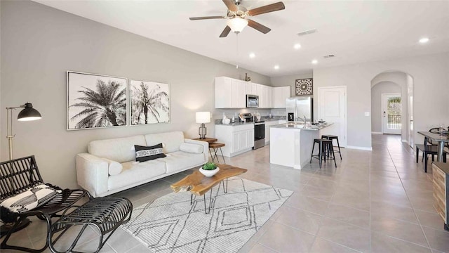 living room with ceiling fan, vaulted ceiling, and light tile patterned flooring