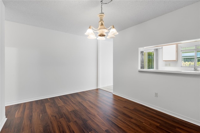 spare room featuring a textured ceiling, a notable chandelier, and wood-type flooring