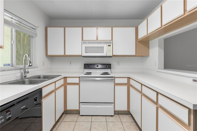 kitchen featuring light tile patterned flooring, white cabinets, sink, and white appliances