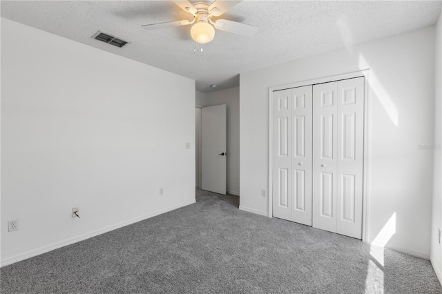 unfurnished bedroom featuring carpet, a textured ceiling, a closet, and ceiling fan