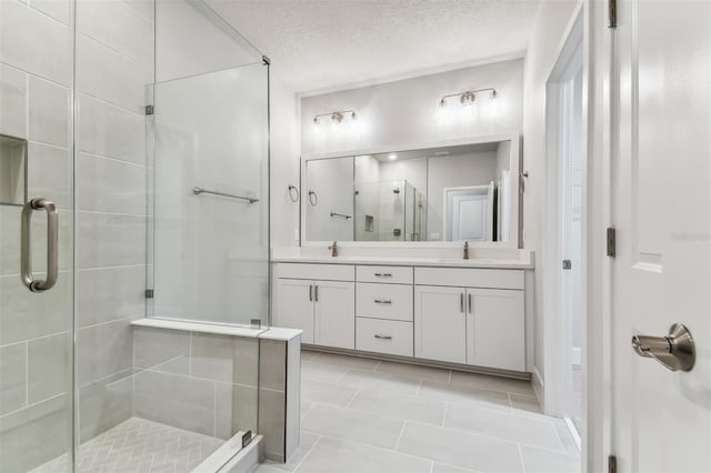 bathroom with tile patterned floors, vanity, a textured ceiling, and walk in shower