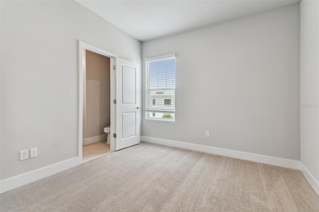 unfurnished bedroom with light colored carpet and ensuite bath