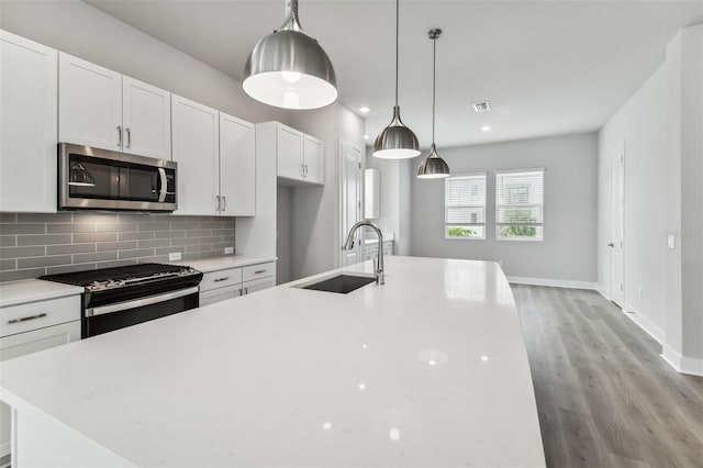 kitchen featuring white cabinets, appliances with stainless steel finishes, pendant lighting, and sink