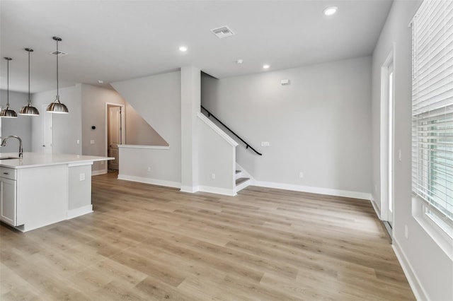 unfurnished living room with light wood-type flooring and sink