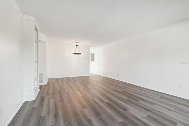 empty room with wood-type flooring and an inviting chandelier