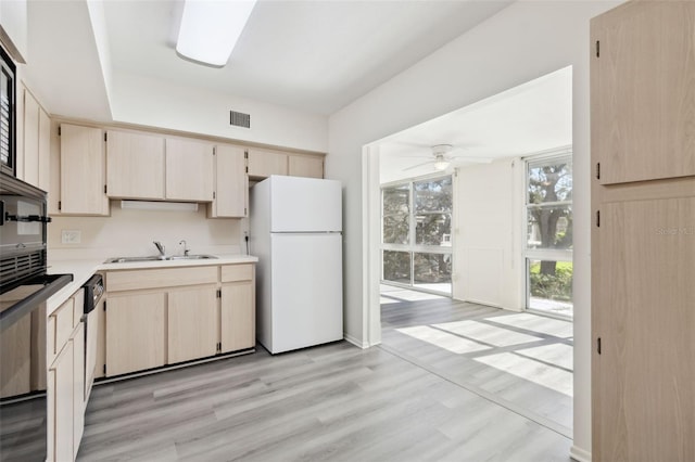 kitchen with light brown cabinets, sink, light wood-type flooring, and white refrigerator