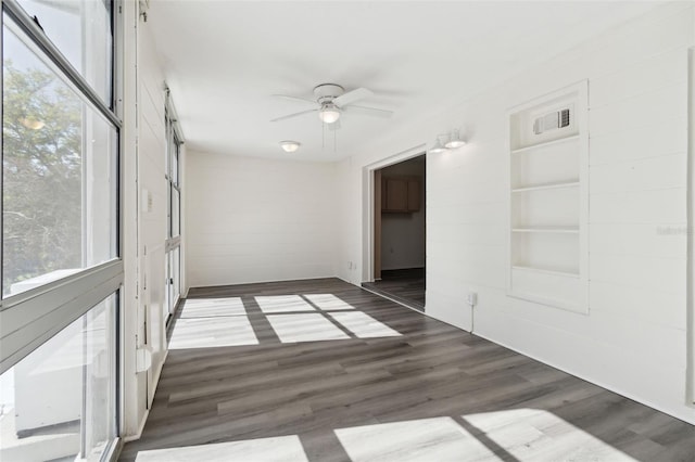 empty room featuring ceiling fan, dark hardwood / wood-style floors, and built in shelves