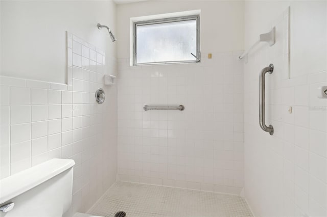 bathroom with tile patterned flooring, toilet, tile walls, and tiled shower