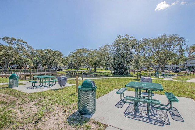 surrounding community with a water view, a patio, and a lawn