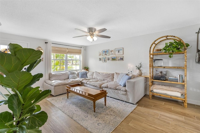 living room featuring light hardwood / wood-style flooring, a textured ceiling, and ceiling fan