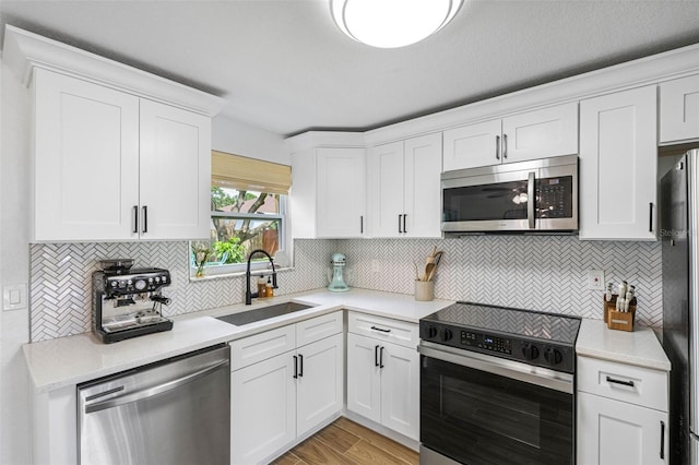 kitchen featuring light wood-type flooring, stainless steel appliances, a sink, and light countertops