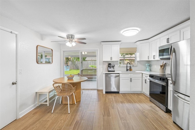 kitchen with light wood finished floors, appliances with stainless steel finishes, light countertops, and a sink