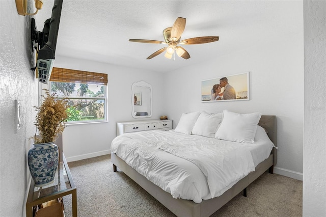 bedroom featuring carpet floors, a textured wall, ceiling fan, and baseboards