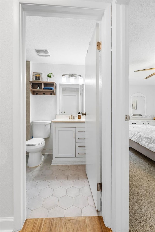 bathroom featuring visible vents, toilet, vanity, ensuite bath, and a textured ceiling